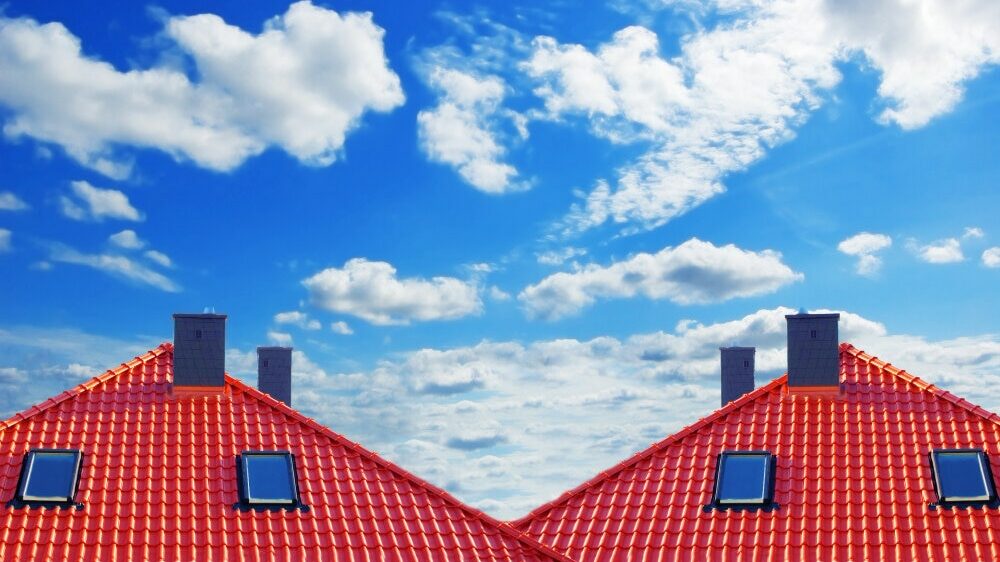 new red roofs with windows and chimneys with a cloudy sky background