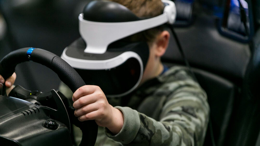 a boy playing a racing game using a virtual reality driving simulator